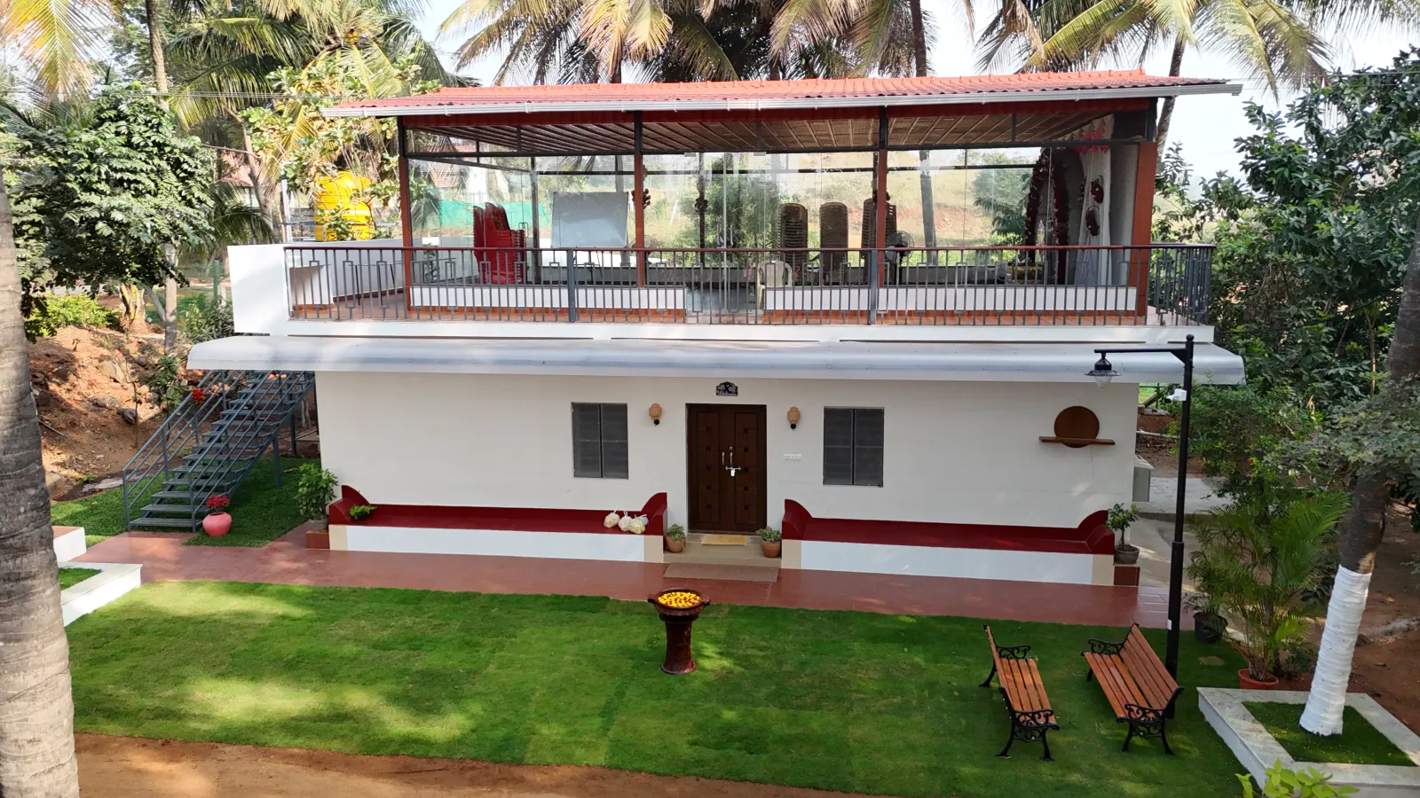 Aerial view of Amal Farms farmhouse with landscaped lawn and seating