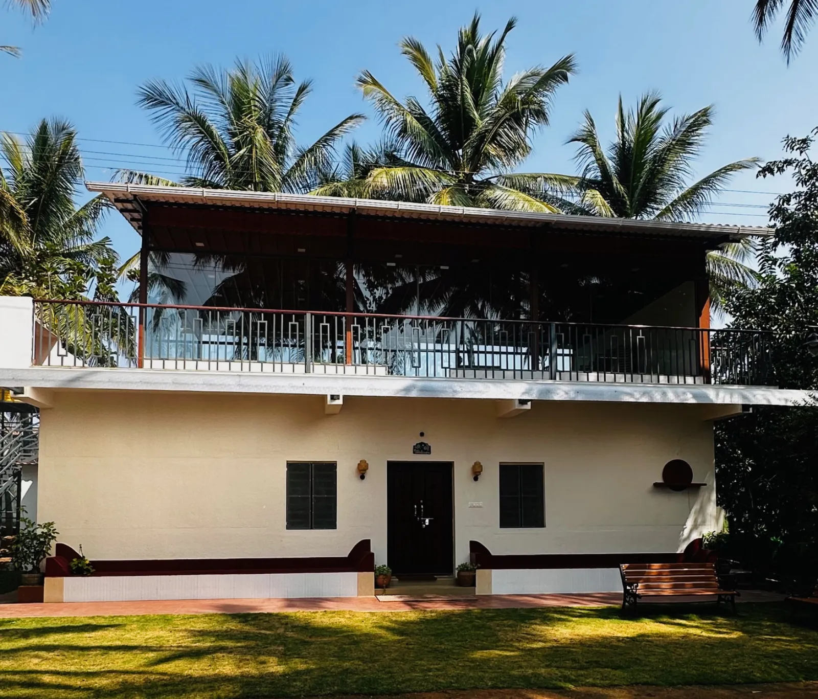 Amal Farms farmhouse front view with blue sky and coconut palms