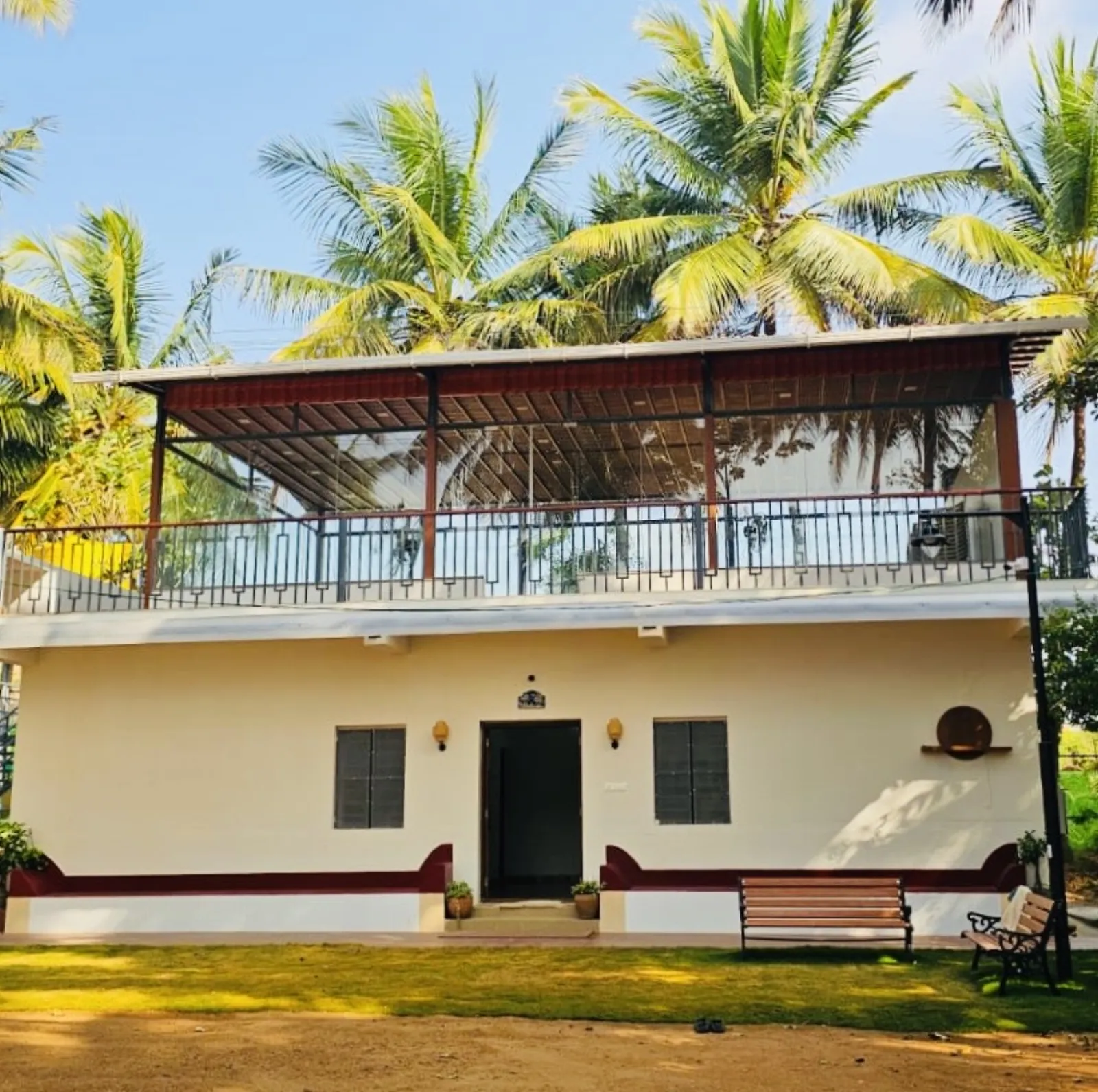 Amal Farms farmhouse on a sunny day with coconut palms