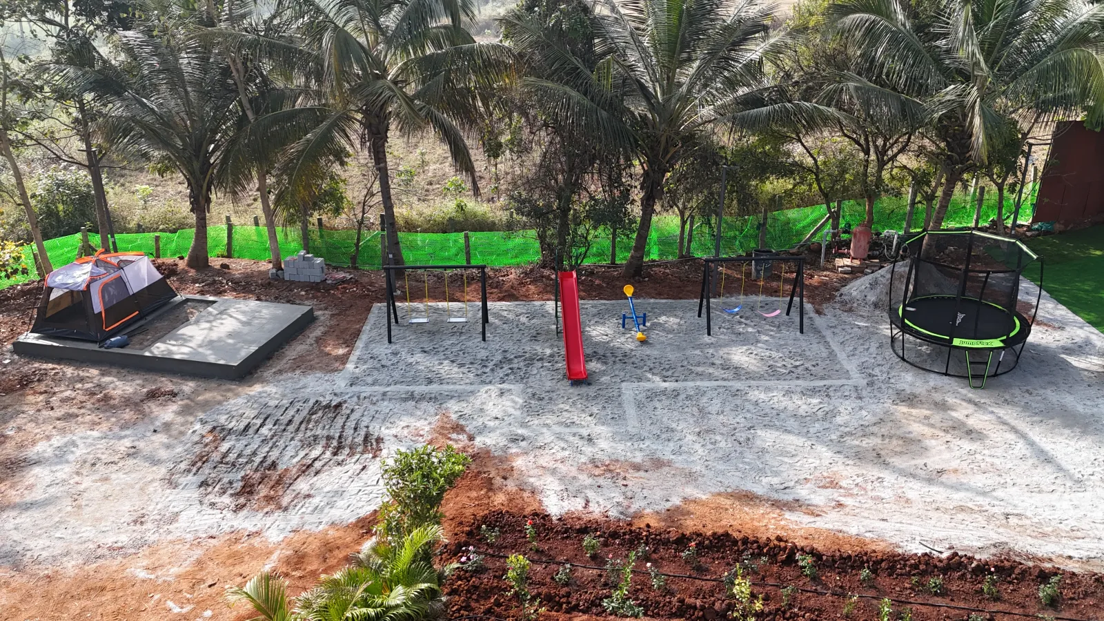 Wide view of the playground area with slides, swings and trampoline at Amal Farms